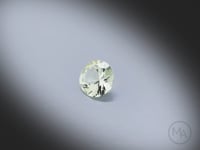 Vidéo d’un Grenat jaune naturel rond facetté de 0.97 ct, originaire de Tanzanie, de couleur jaune-vert très léger, presque incolore, pierre rare tournant sur un fond gris clair.