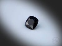 Vidéo d’un Spinelle noir naturel coussin carré facetté de 1.58 ct, originaire de Thaïlande, de couleur noir sombre, pierre fine tournant sur un fond gris clair.