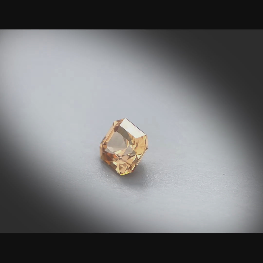 Vidéo d’un zircon naturel rectangle à pans coupés facetté de 1.65 ct, originaire de Tanzanie, mettant en valeur sa teinte brun orangé prononcée et ses reflets lumineux.