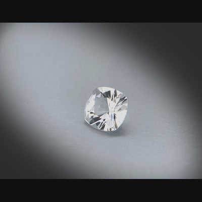 Vidéo d’une topaze incolore naturelle non traitée, taille coussin carré facettée de 1.87 ct, d'une pureté sans inclusion à la loupe 10x, tournant sur un fond gris clair.