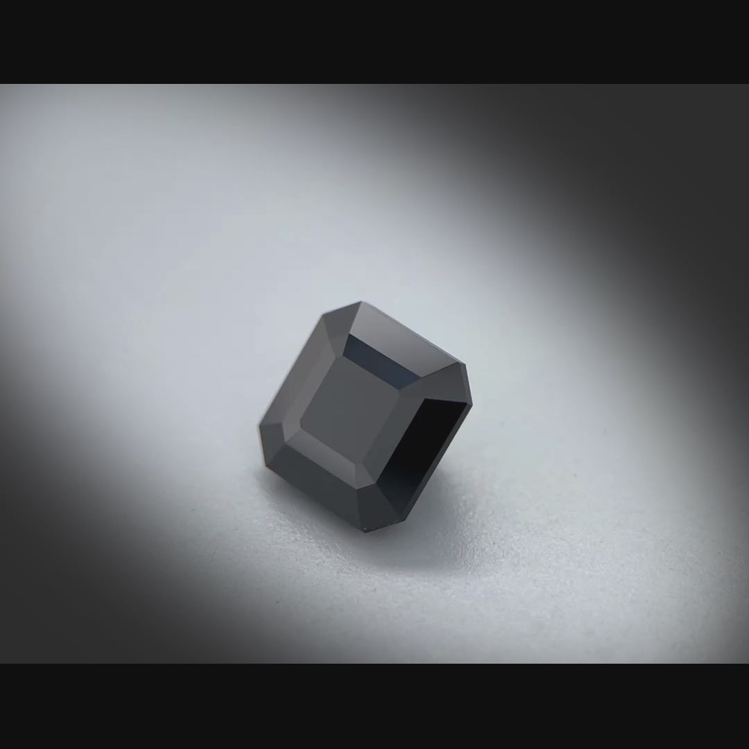 Vidéo d’un spinelle naturel noir carré à pans coupés de 3.88 ct, facetté, originaire de Thaïlande, tournant à 360 degrés sur fond gris clair.
